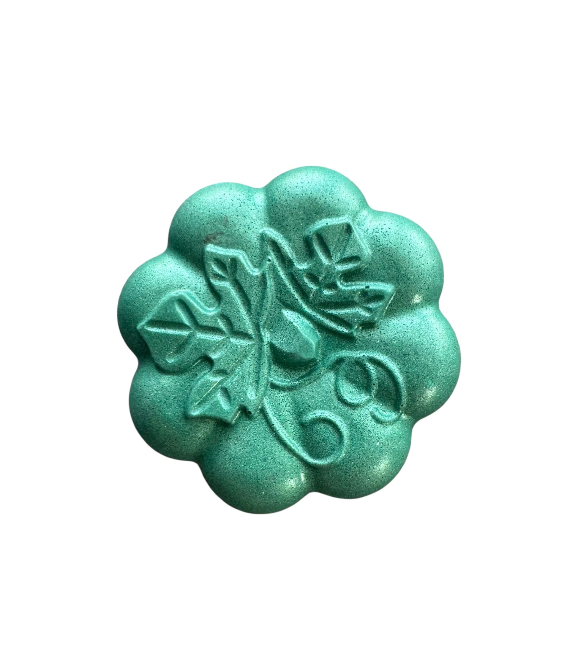 Turquoise flower-shaped object with embossed design on a white background