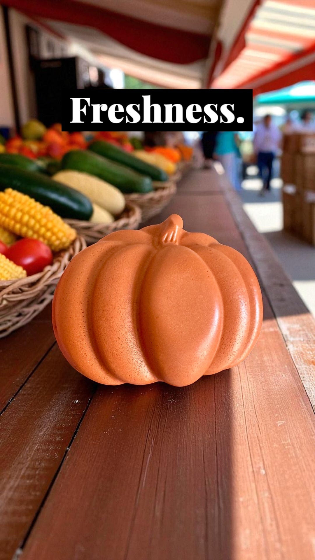 Decorative orange pumpkin on a wooden table with fresh vegetables in the background, labeled 'Freshness'.
