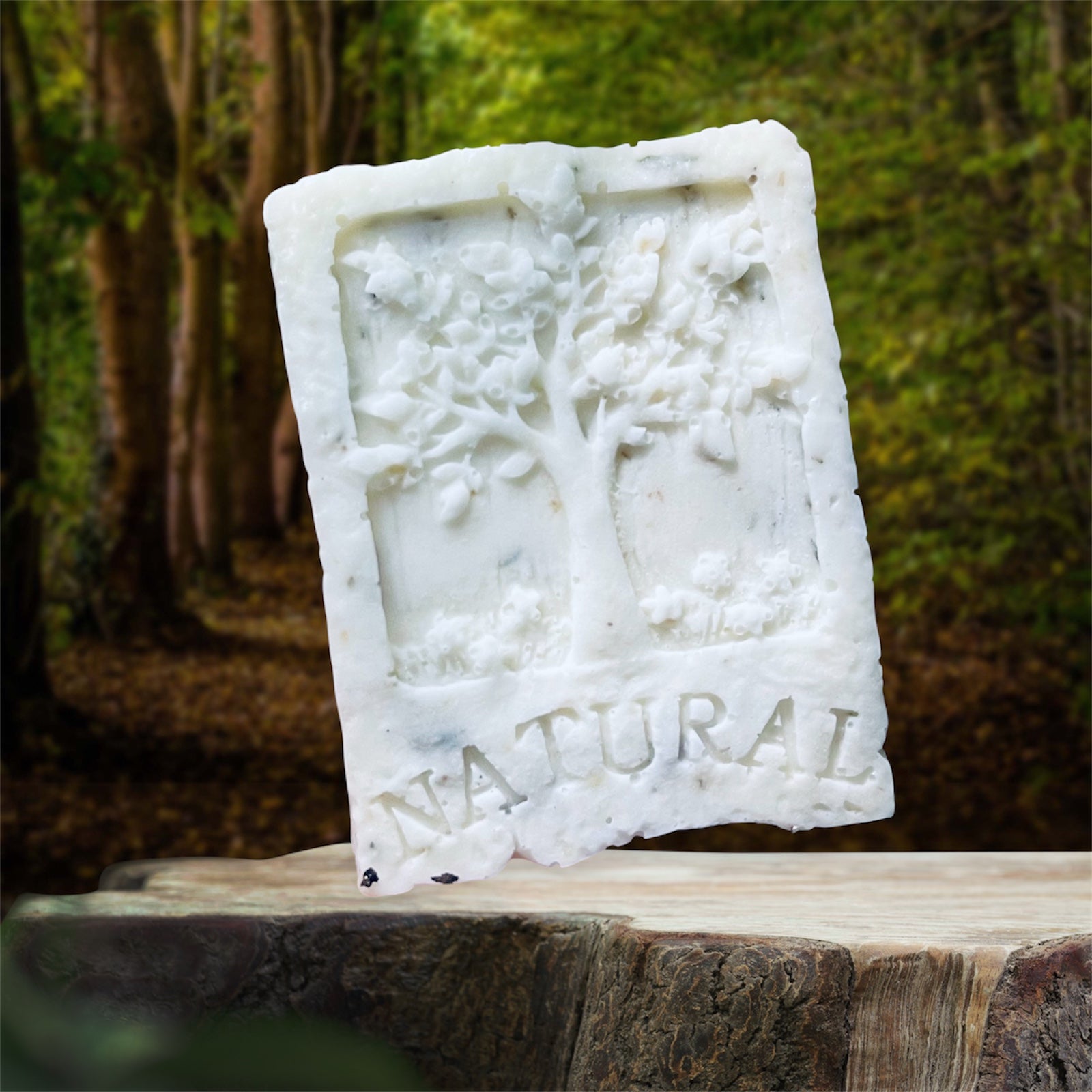 Bar of natural soap with tree design on a wooden surface outdoors