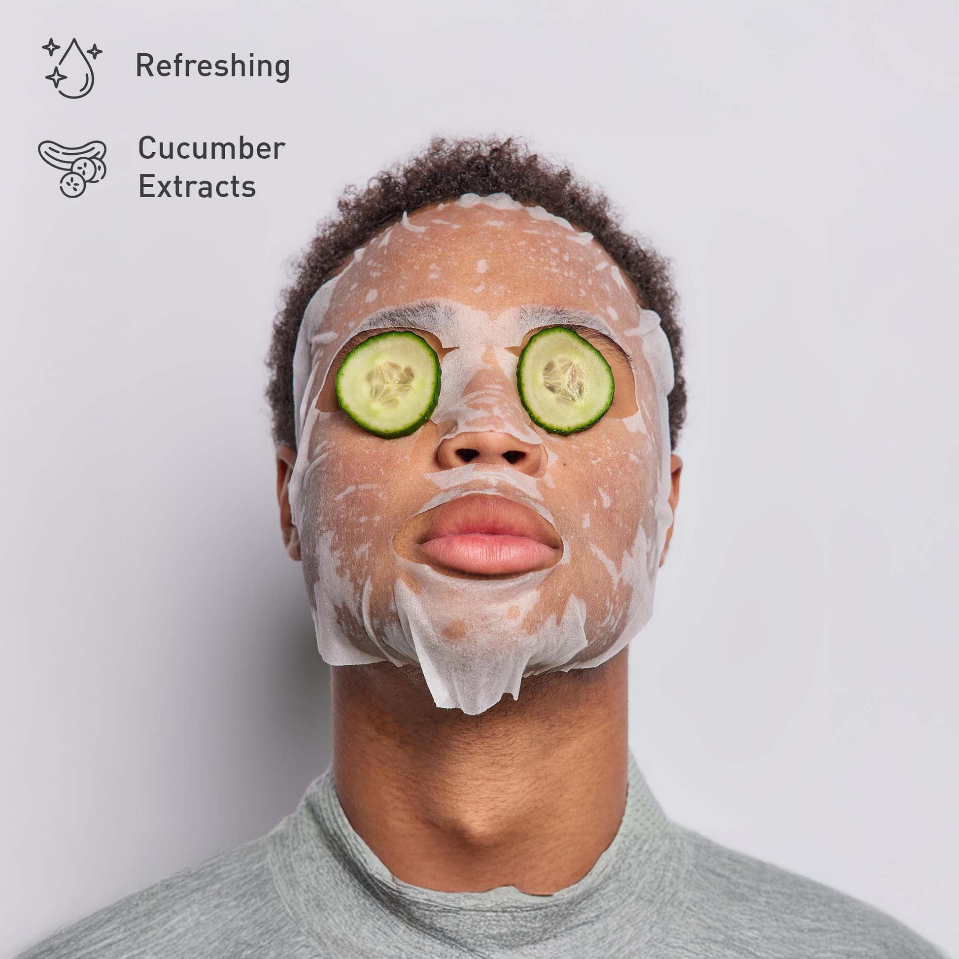 Person with a facial mask and cucumber slices on a plain background