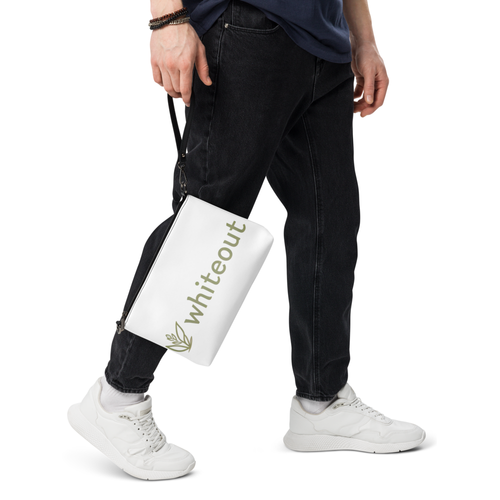 Person wearing black jeans and white sneakers holding a 'Whiteout' branded bag.