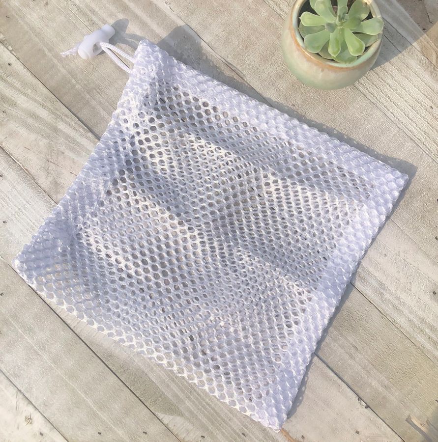 Clear mesh bag on a wooden surface with a small plant in the background