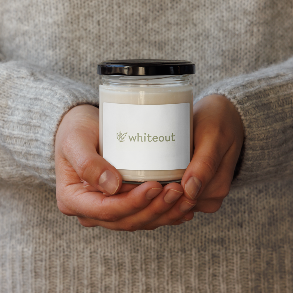 Person holding a candle labeled 'whiteout' against a neutral background